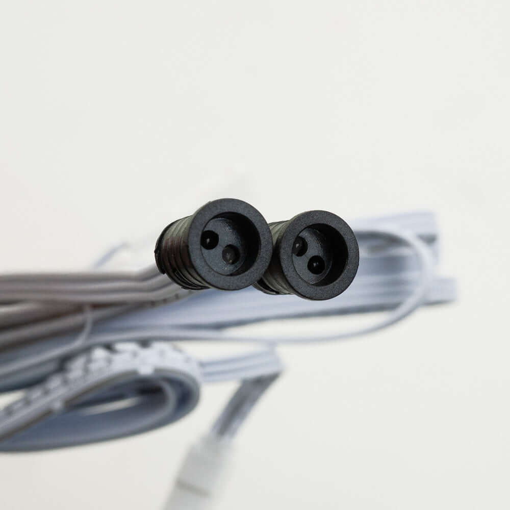 Close-up of a double-headed connector for a sensor switch, featuring two black round sockets and gray cable.