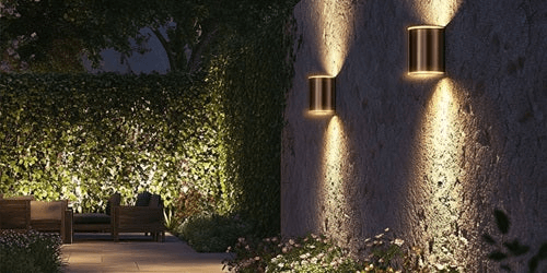 Elegant outdoor wall lights illuminating a garden setting at night, creating a cozy and inviting atmosphere.