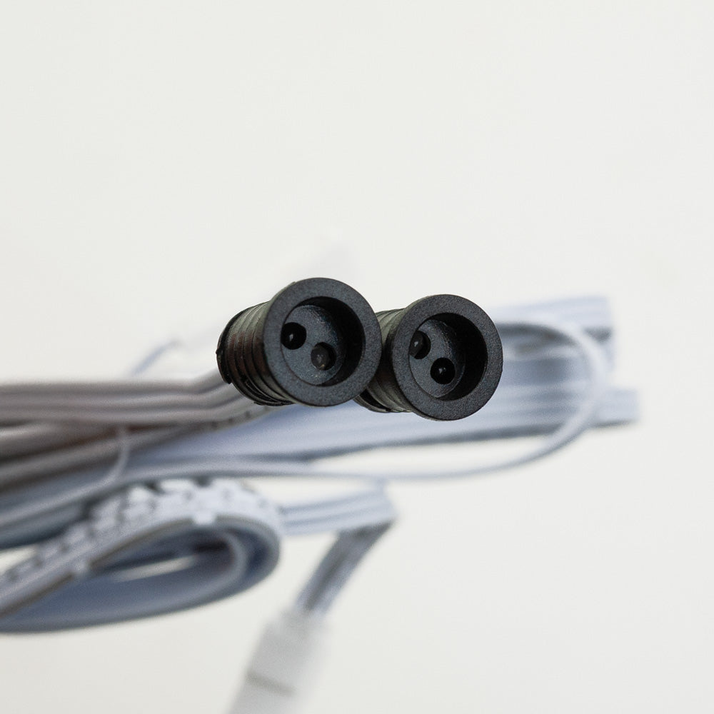 Close-up of a double-headed connector for a sensor switch, featuring two black round sockets and gray cable.
